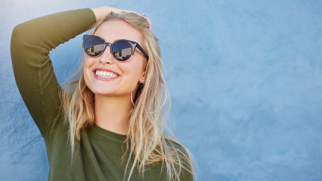 Woman in sunglasses with one hand on head