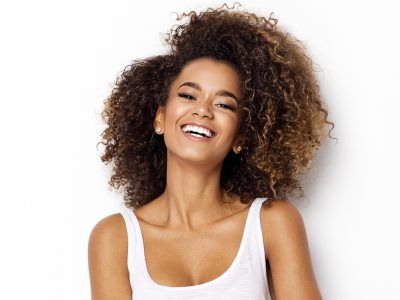 woman with curly hair in white shirt smiling